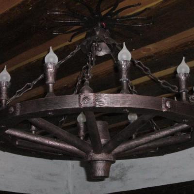 Stalowy żyrandol w formie koła starej bryczki. Wyprodukowany na potrzeby stadniny koni. Całość nitowana, szczegóły odtworzone ze stuprocentową dbałością. Faktura imitująca strukturę drewna.